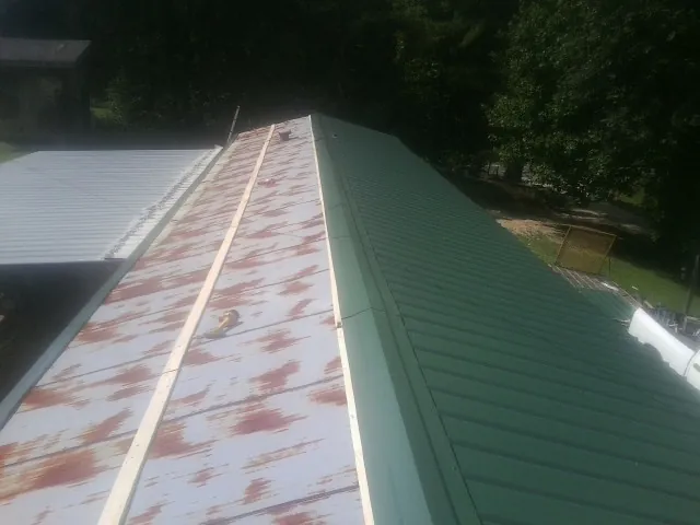 Old rusted panels beside newly installed green metal roofing — Wind Damage Roof Repair by Roofing Brothers in Gaithersburg