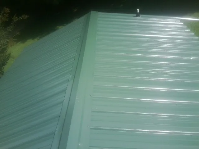 New green metal panels meeting at the ridge of a roof — Flat Roof Repair work by our crew in Gaithersburg