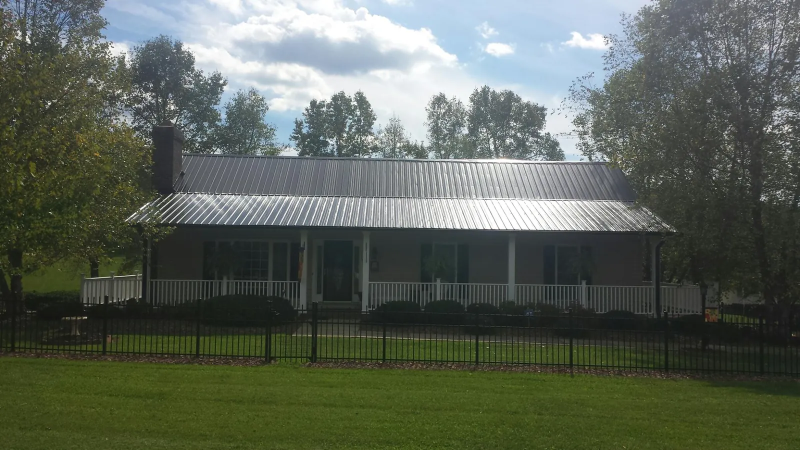 Gray metal roof on a brick ranch with a full width front porch — Gutter Guard Installation work by our crew in Gaithersburg