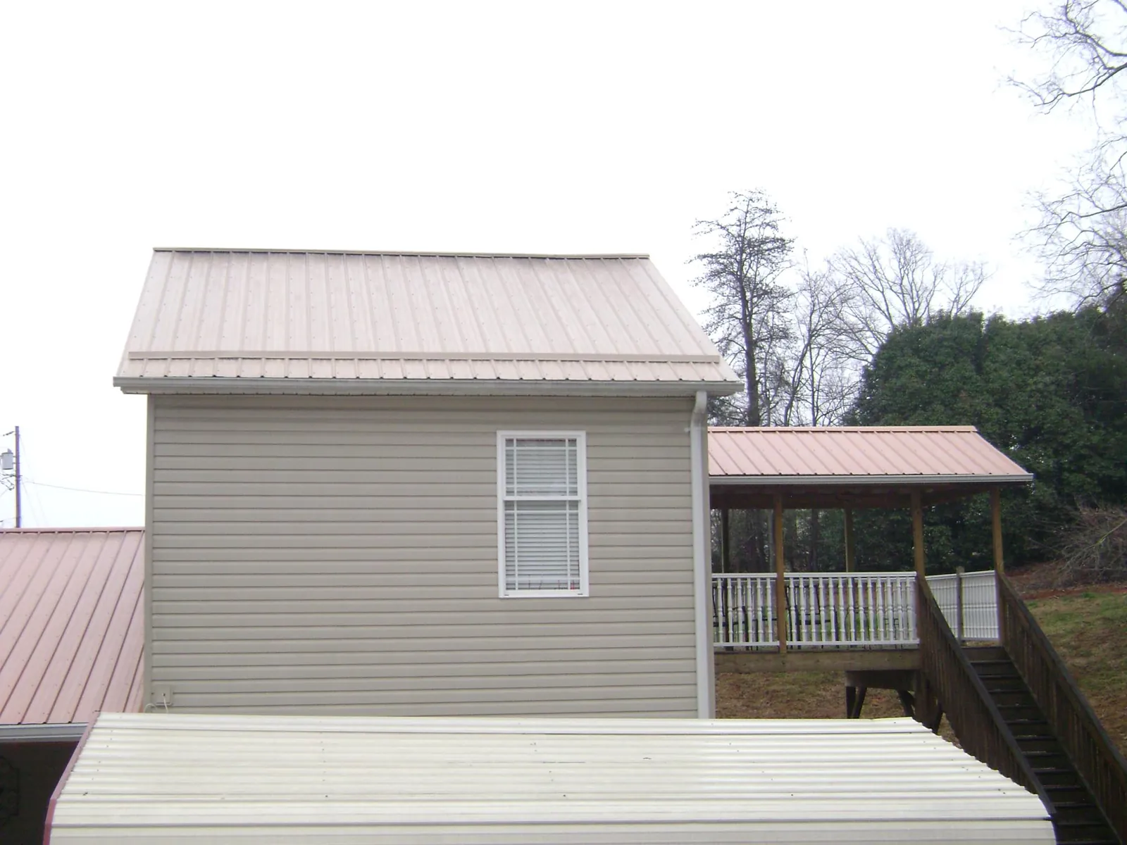 Tan metal roofs on a two story addition and attached porch, from a Roof Replacement job in Gaithersburg