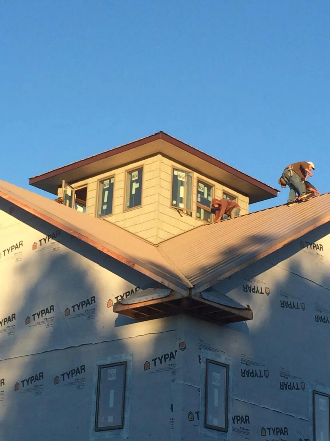 Roofers working around a rooftop cupola on a new metal roof at sunset — Roof Waterproofing in Gaithersburg by Roofing Brothers